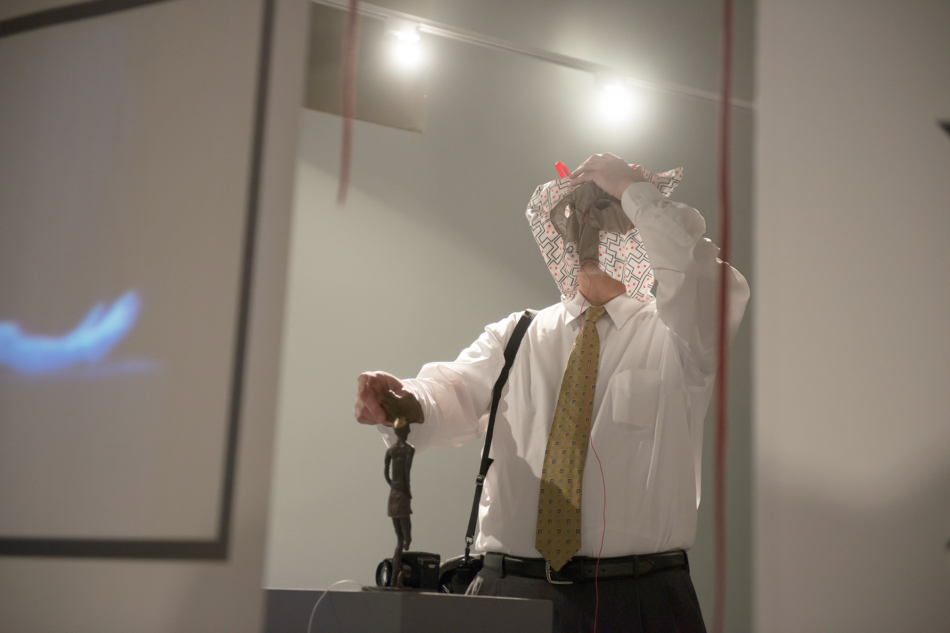 Performance view of the artist wrapping printed fabric around his head