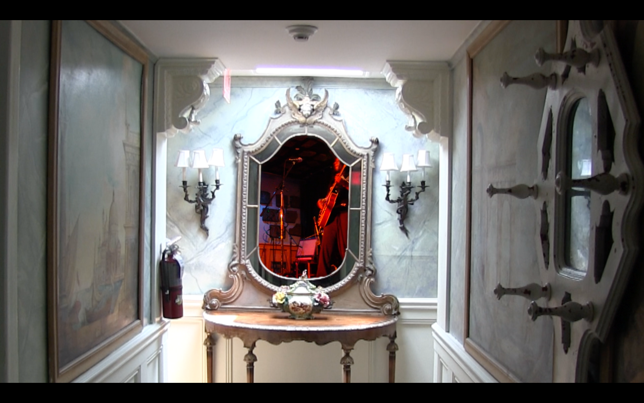 Wide still from eye, virus showing a performer reflected in an ornate mirror