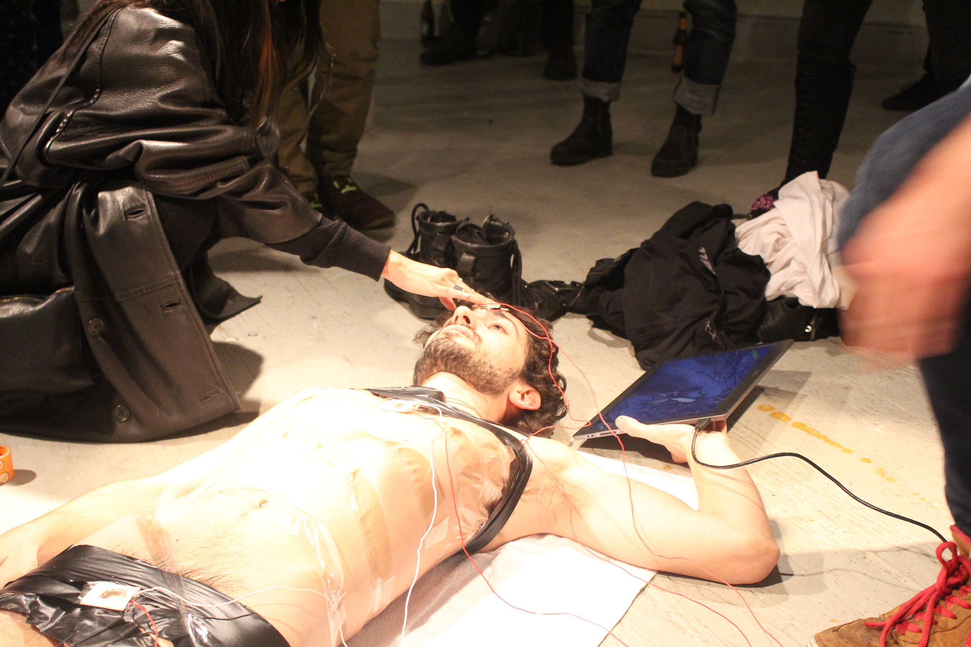 Participant touching a sensor near the artist's forehead while the artist holds a monitor